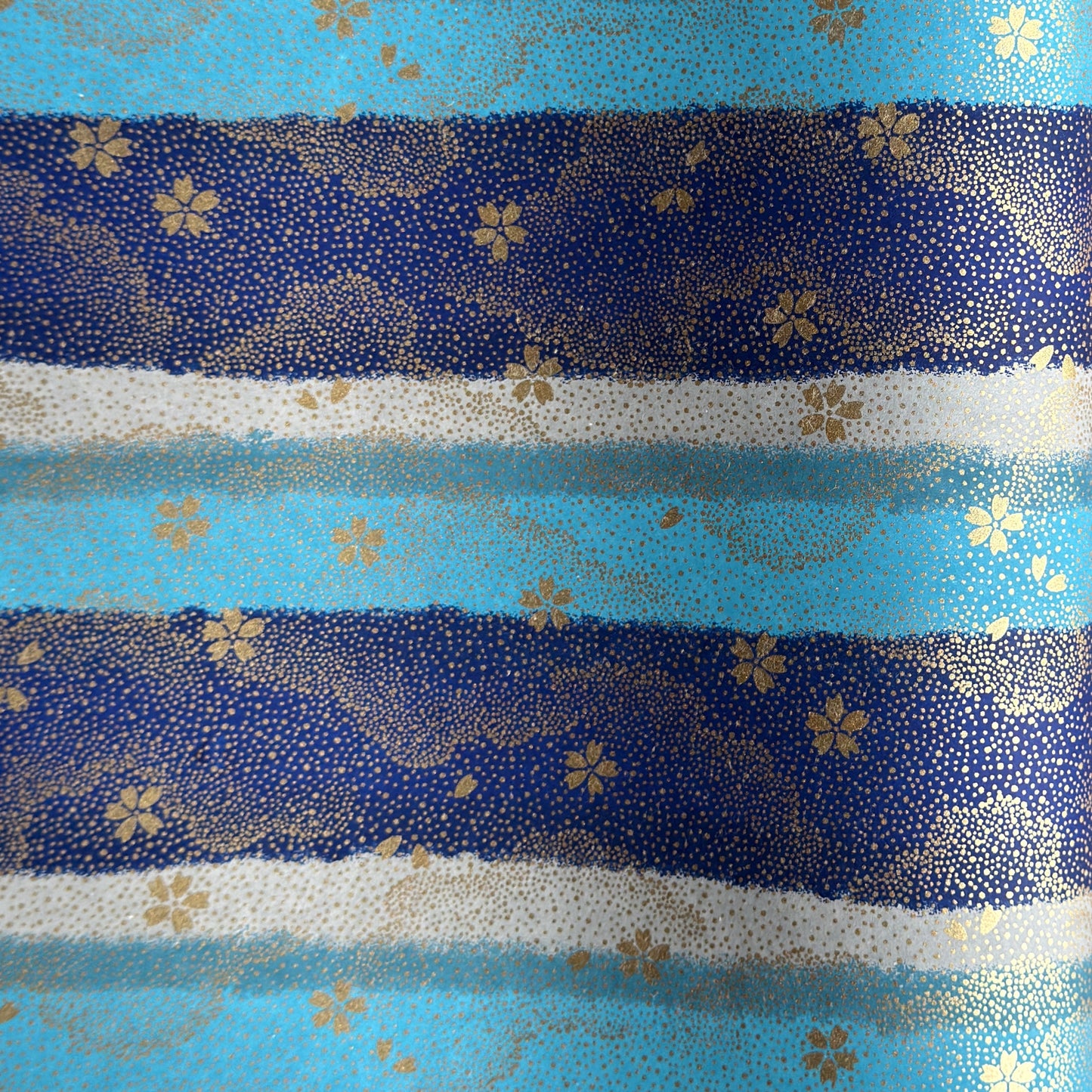 japanese chiyogami paper in stripes of blue, turquoise and grey with gold clouds and flowers