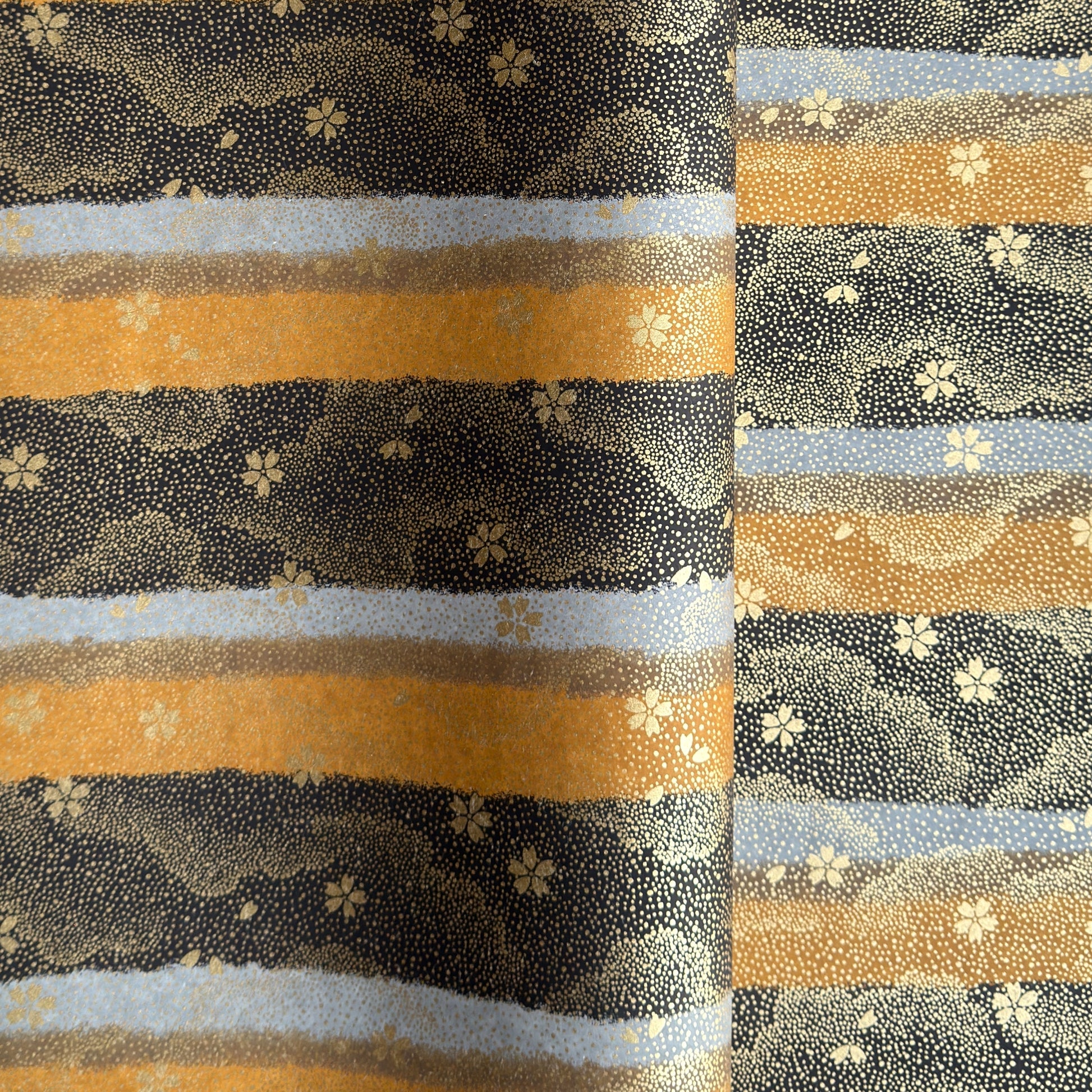 japanese chiyogami paper in stripes of black, brown, ochre and grey with gold clouds and flowers