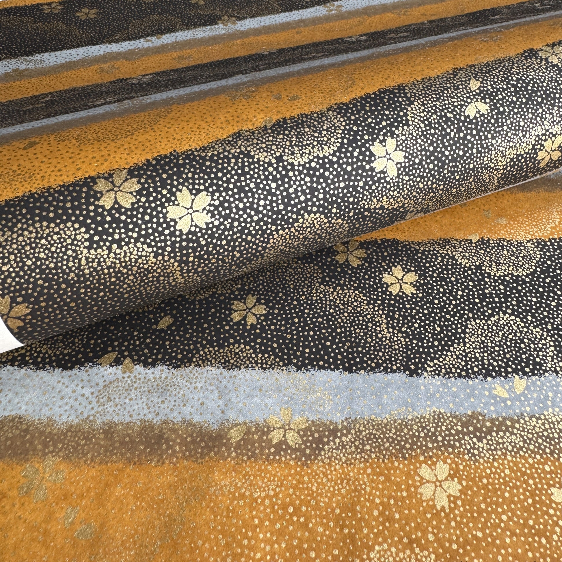 japanese chiyogami paper in stripes of black, brown, ochre and grey with gold clouds and flowers