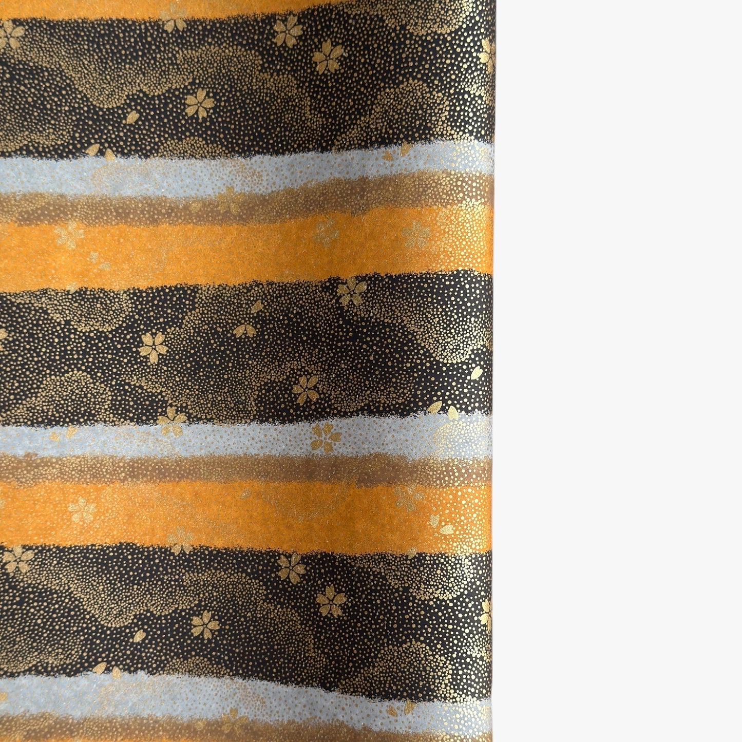 japanese chiyogami paper in stripes of black, brown, ochre and grey with gold clouds and flowers