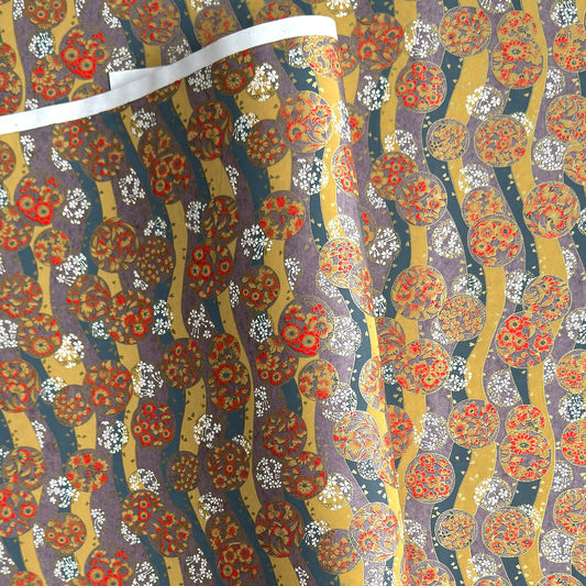 Japanese silkscreen chiyogami paper with a traditional botanical circle motif in tones of mustard, inky blue, lilac and gold.
