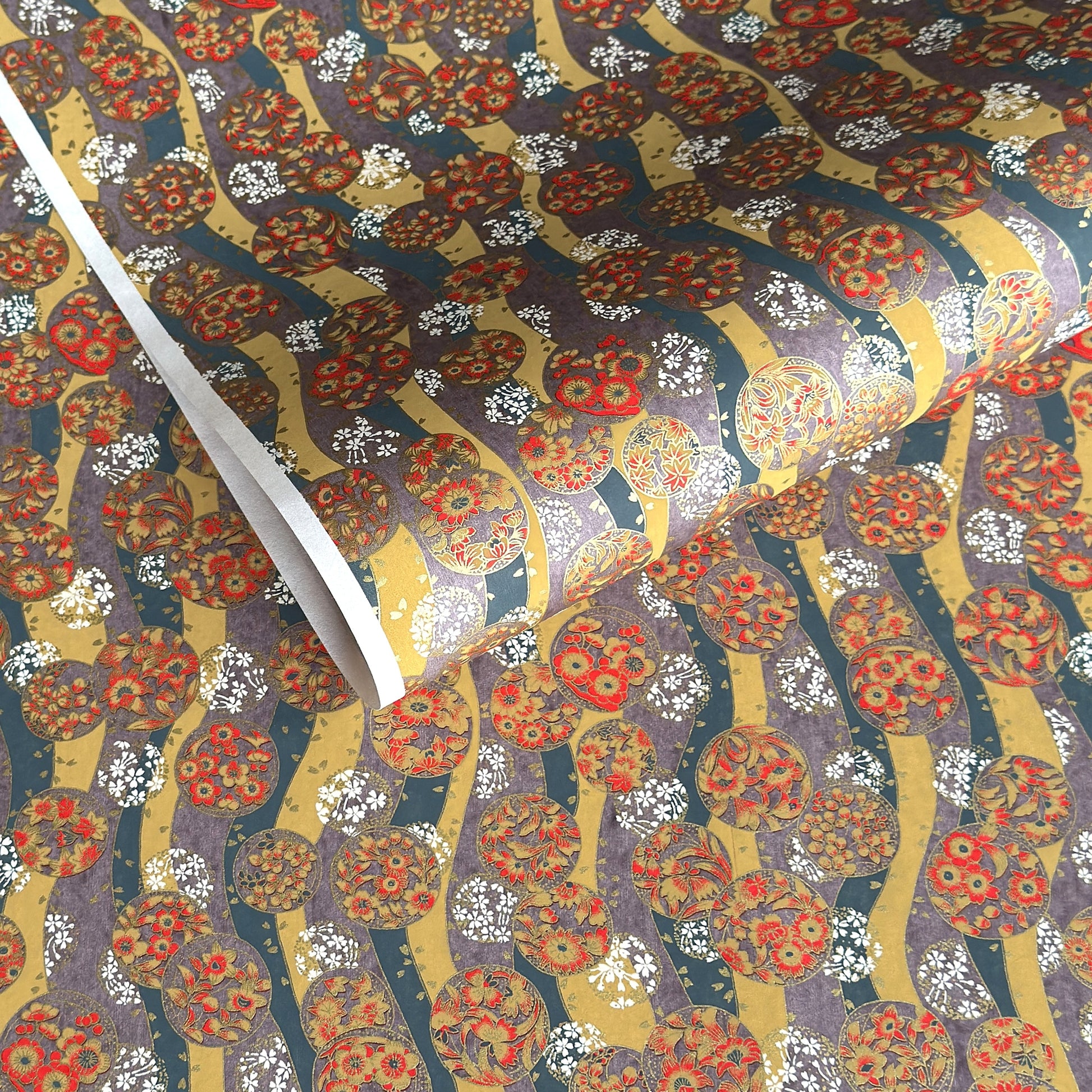 Japanese silkscreen chiyogami paper with a traditional botanical circle motif in tones of mustard, inky blue, lilac and gold.