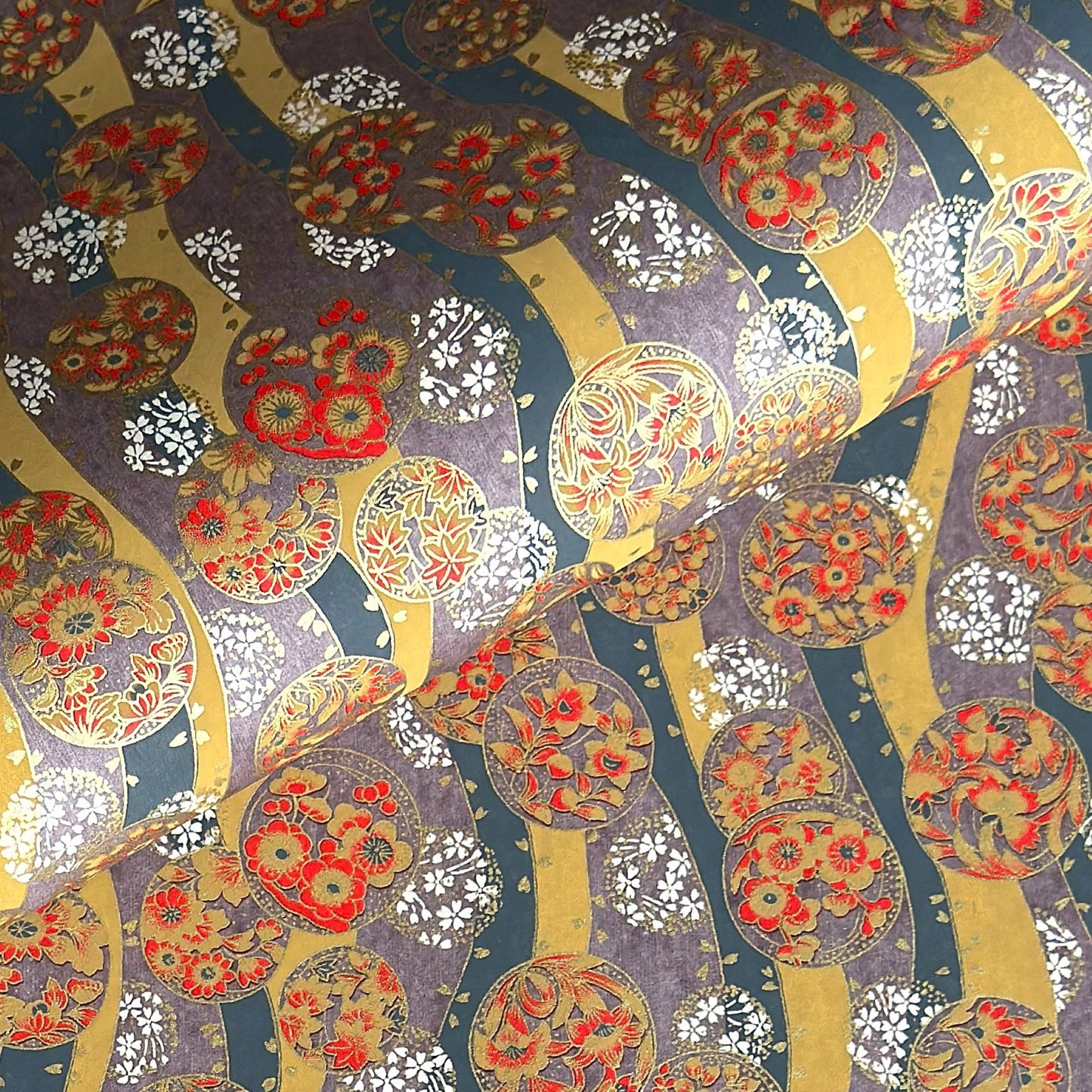 Japanese silkscreen chiyogami paper with a traditional botanical circle motif in tones of mustard, inky blue, lilac and gold.