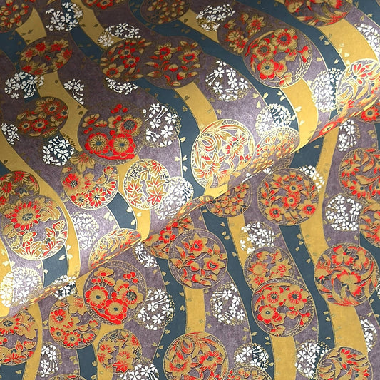 Japanese silkscreen chiyogami paper with a traditional botanical circle motif in tones of mustard, inky blue, lilac and gold.