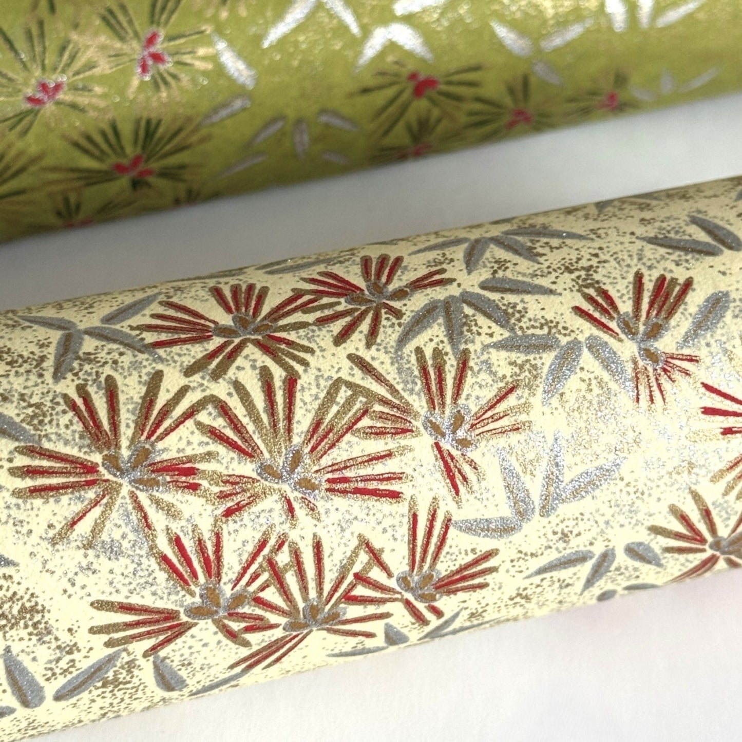 Pattern of scattered pine needles (matsuba) in gold and silver on a cream backdrop. Japanese chiyogami paper