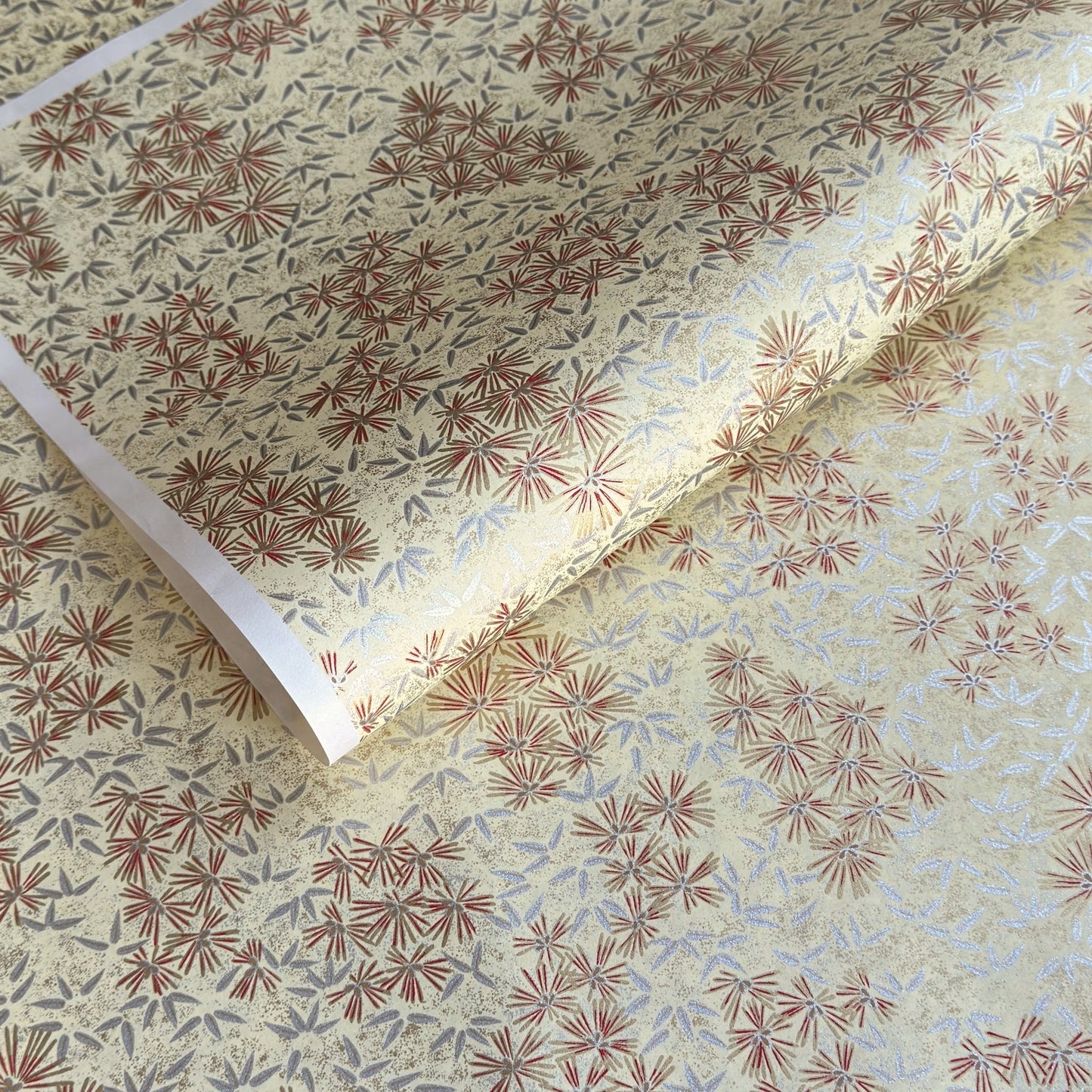 Pattern of scattered pine needles (matsuba) in gold and silver on a cream backdrop. Japanese chiyogami paper