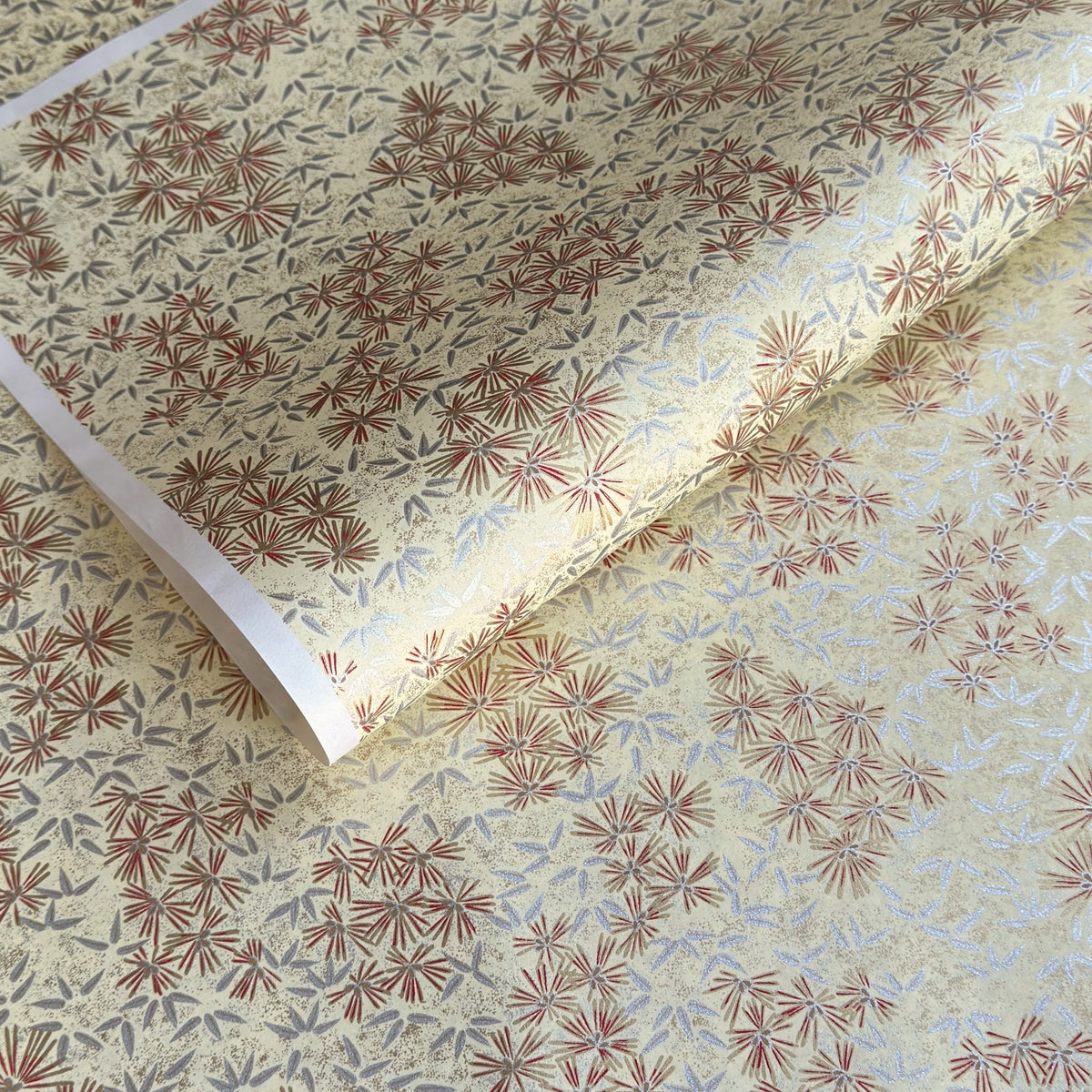 Pattern of scattered pine needles (matsuba) in gold and silver on a cream backdrop. Japanese chiyogami paper