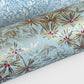 Japanese chiyogami paper silkscreen printed with gold pine needle design on a soft aqua backdrop.