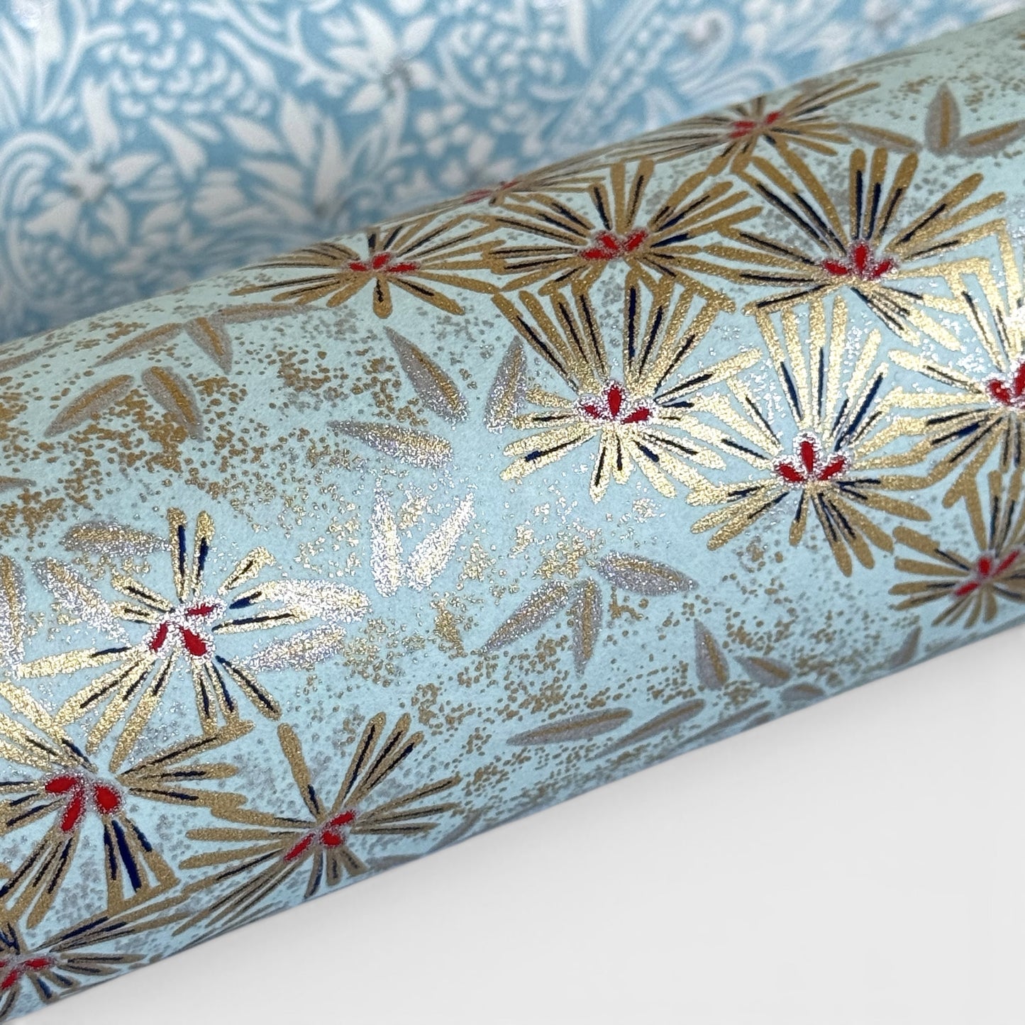 Japanese chiyogami paper silkscreen printed with gold pine needle design on a soft aqua backdrop.