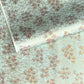 Japanese chiyogami paper silkscreen printed with gold pine needle design on a soft aqua backdrop.