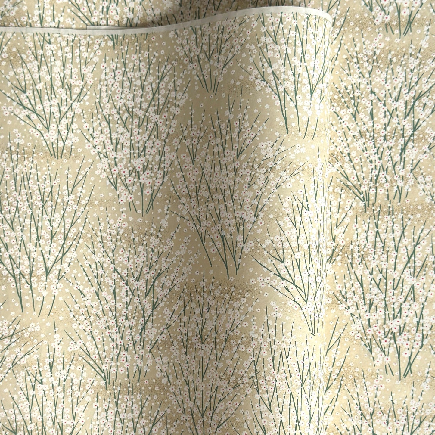 a sheet of Japanese silkscreen printed chiyogami paper with a delicate design of tufts of meadow grasses in flower in white, green on a cream background