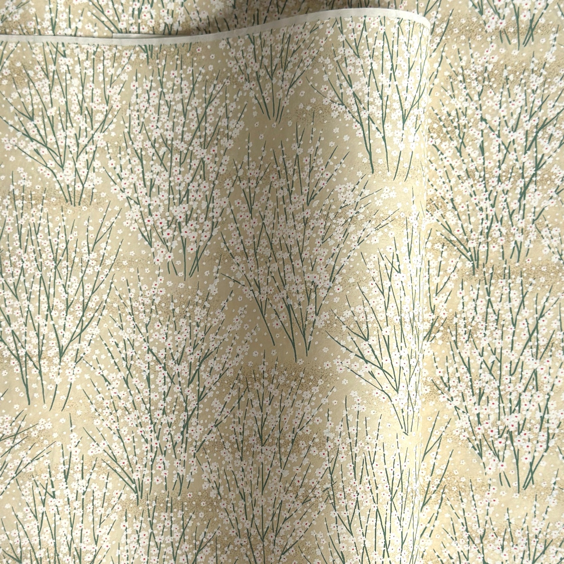 a sheet of Japanese silkscreen printed chiyogami paper with a delicate design of tufts of meadow grasses in flower in white, green on a cream background