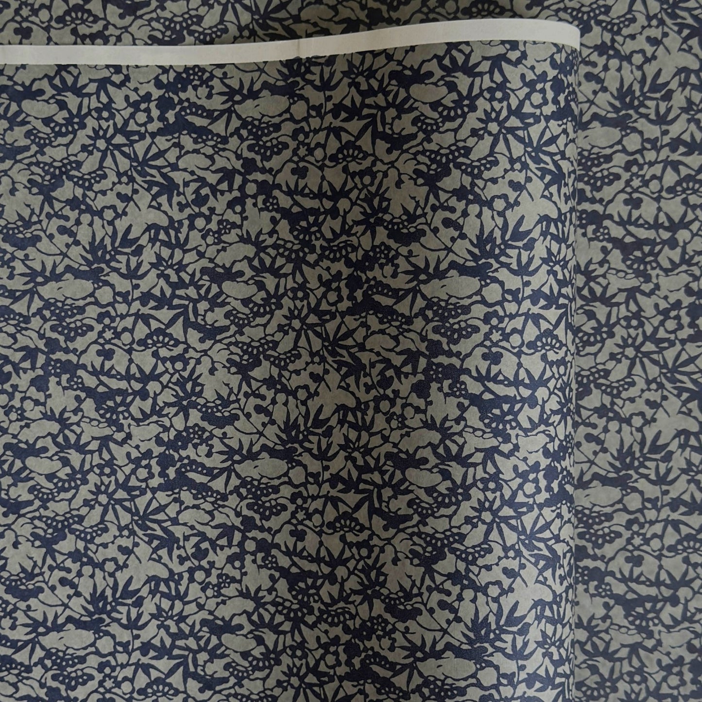 a sheet of Japanese chiyogami yuzen paper with a small abstract pattern in midnight blue on grey