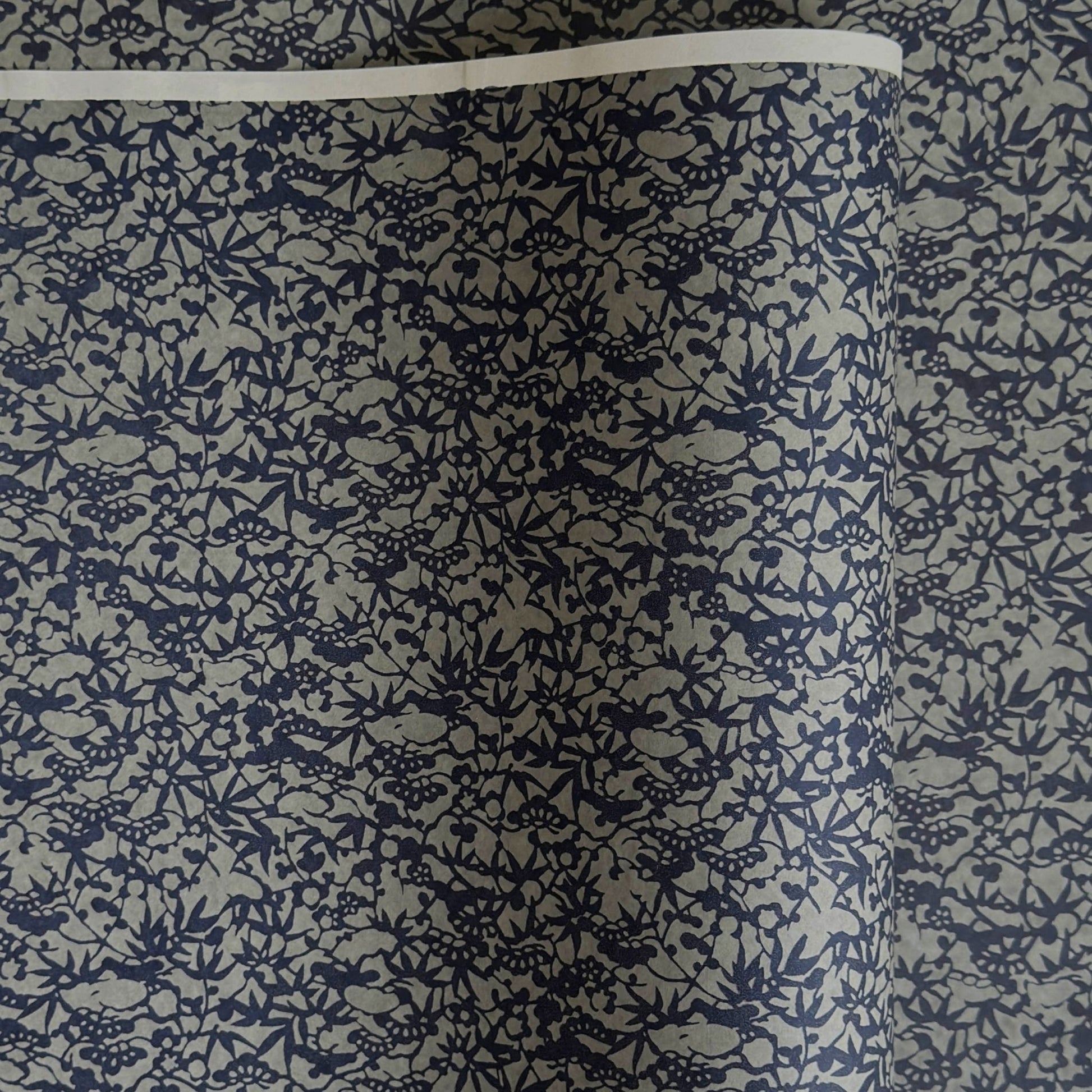 a sheet of Japanese chiyogami yuzen paper with a small abstract pattern in midnight blue on grey