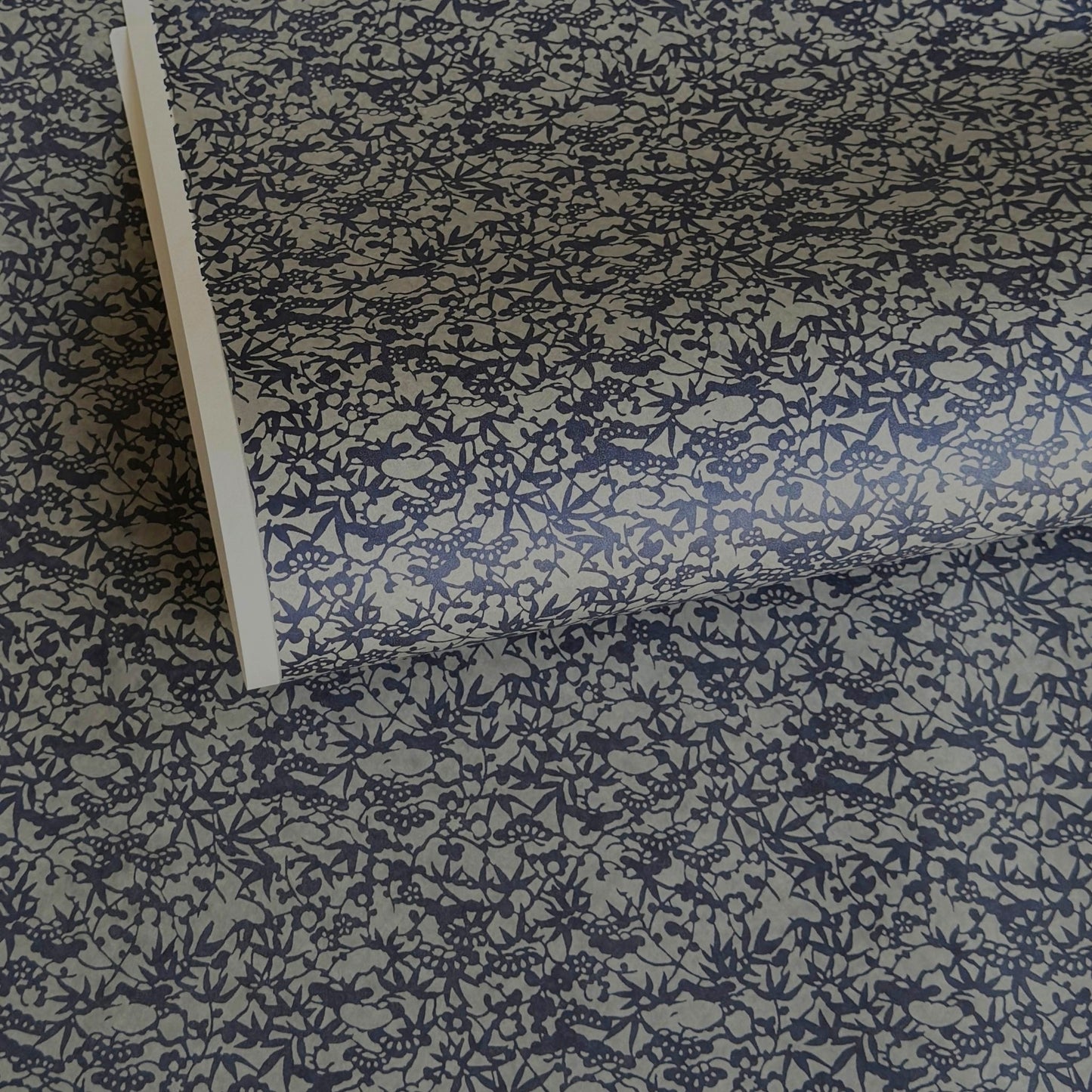a sheet of Japanese chiyogami yuzen paper with a small abstract pattern in midnight blue on grey