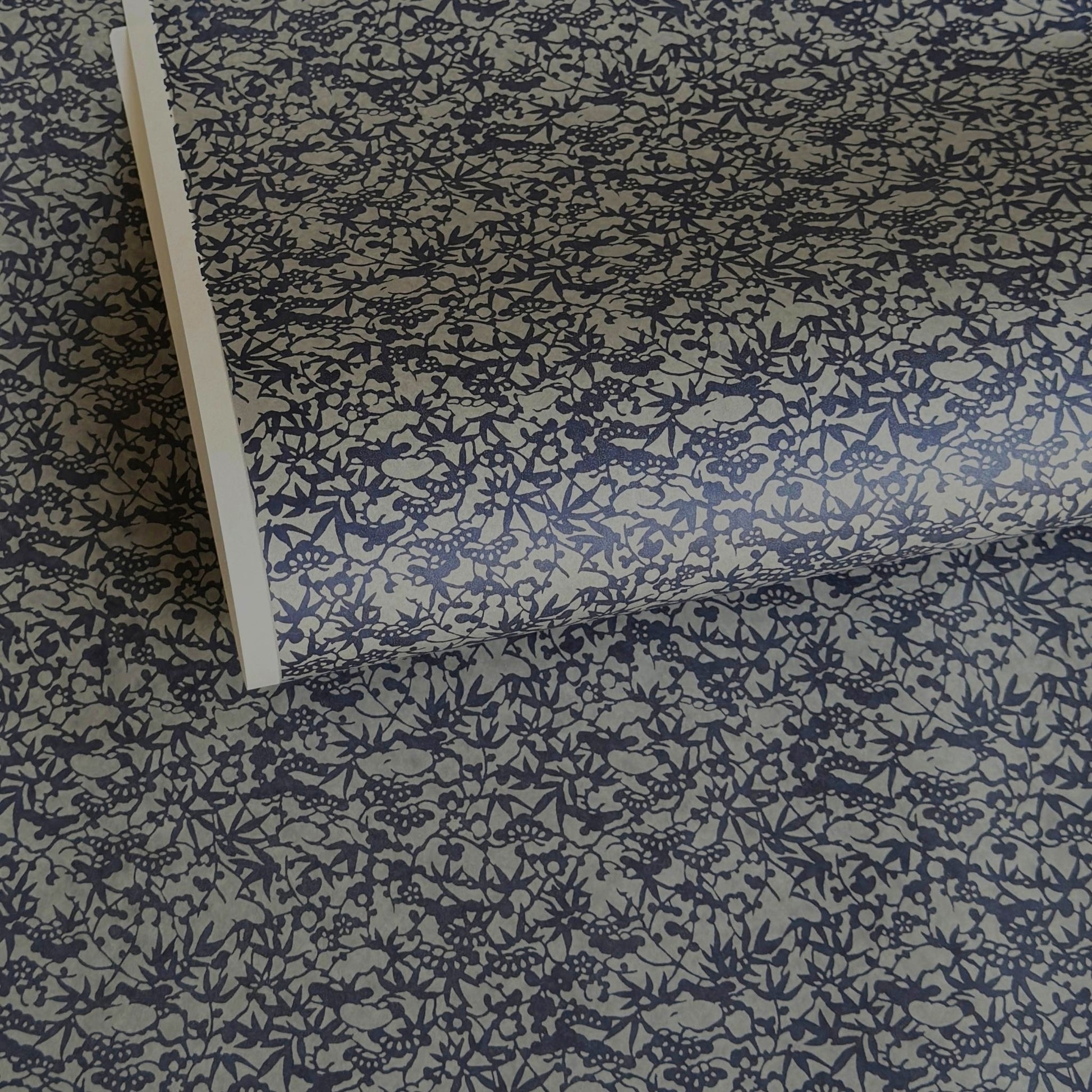 a sheet of Japanese chiyogami yuzen paper with a small abstract pattern in midnight blue on grey