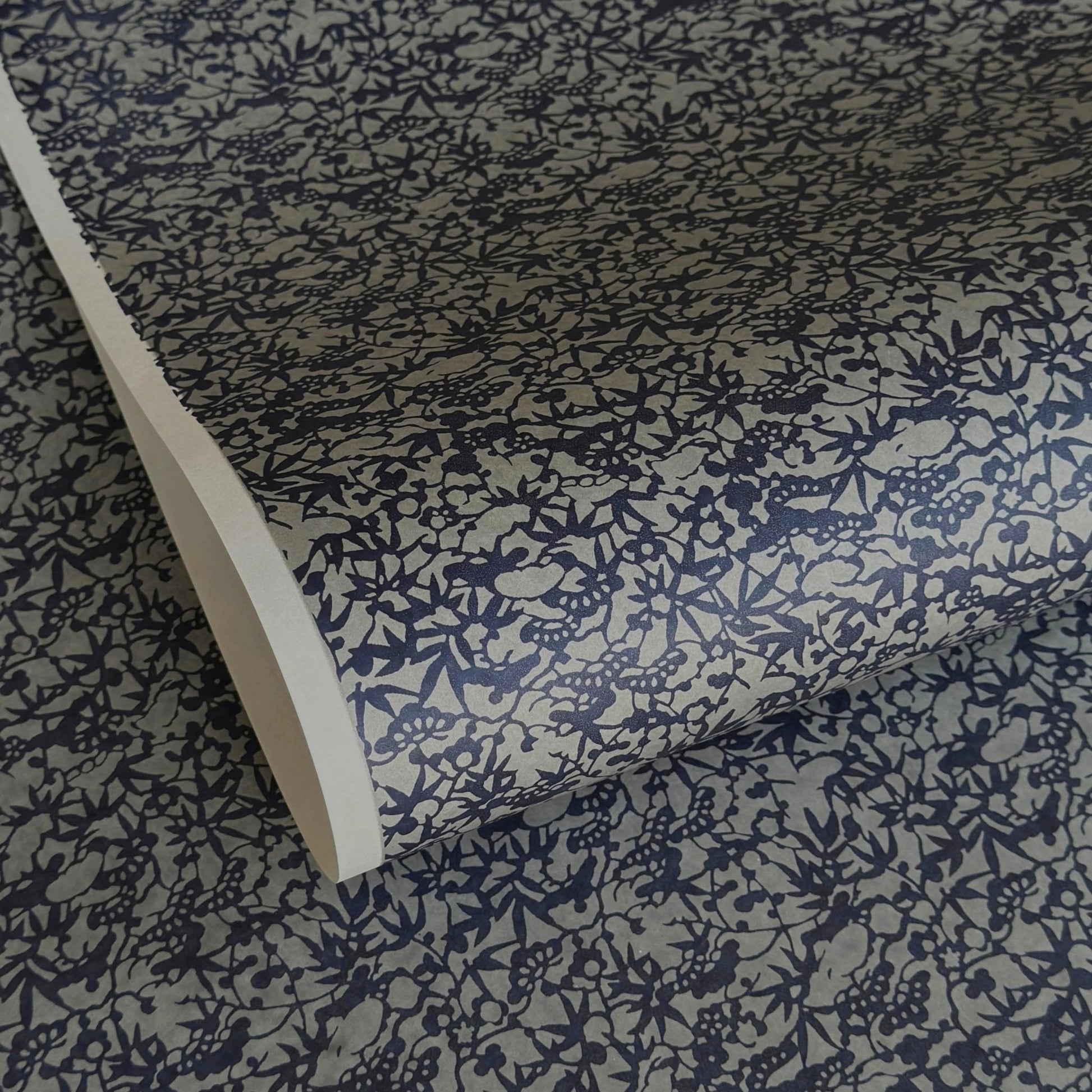 a sheet of Japanese chiyogami yuzen paper with a small abstract pattern in midnight blue on grey