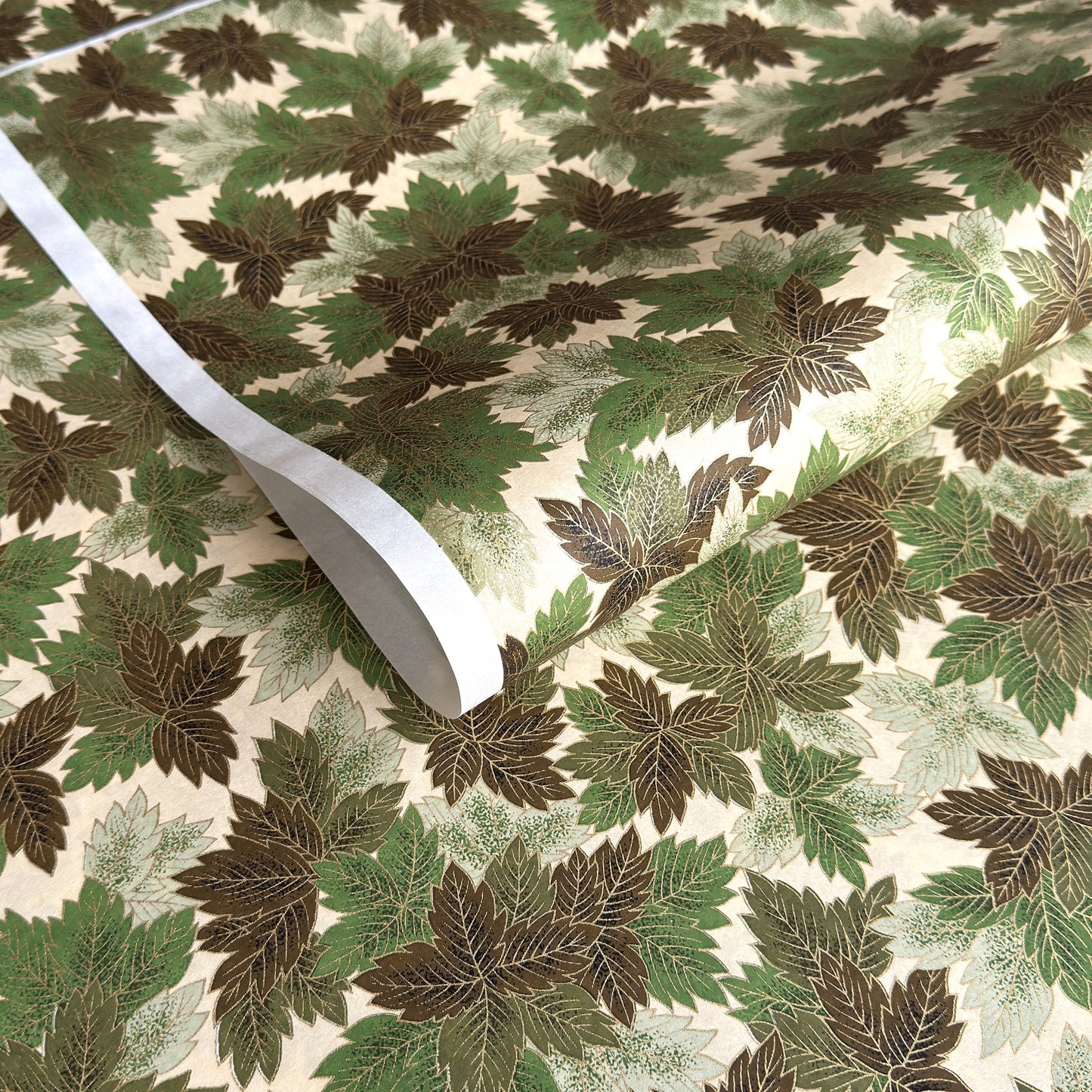 Japanese chiyogami paper with a pattern of green leaves in various tones with gold accent.