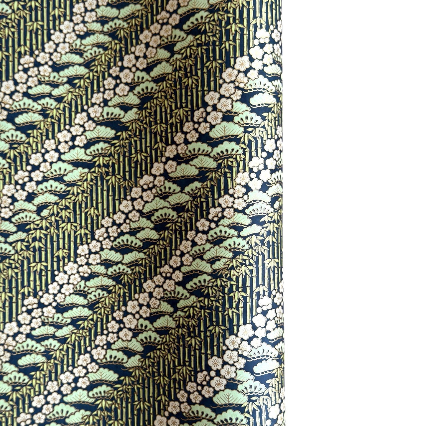 a sheet of Japanese silkscreen printed chiyogami paper with a design of trees, bamboo and plum blossom in a palette of mint green, white and dark indigo