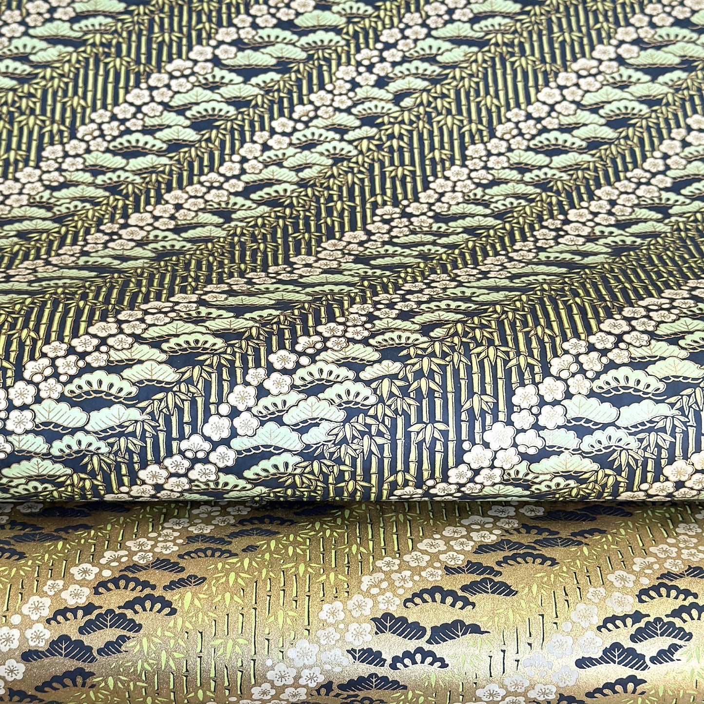 a sheet of Japanese silkscreen printed chiyogami paper with a design of trees, bamboo and plum blossom in a palette of mint green, white and dark indigo