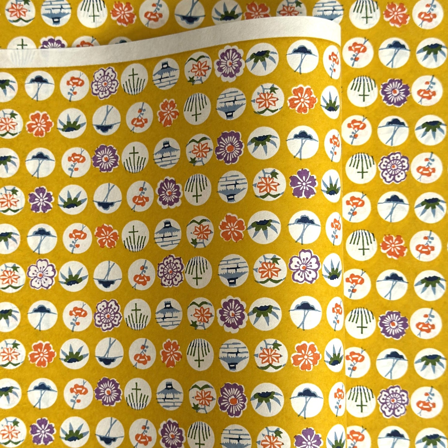 japanese silk-screen handmade paper showing circles of traditional motifs on yellow backdrop