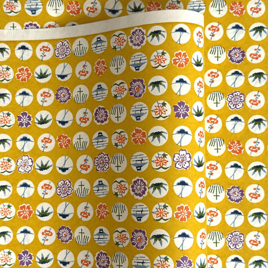 japanese silk-screen handmade paper showing circles of traditional motifs on yellow backdrop