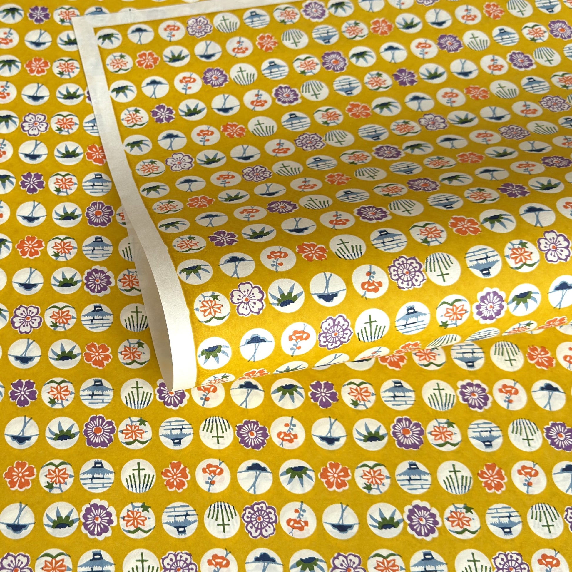 japanese silk-screen handmade paper showing circles of traditional motifs on yellow backdrop