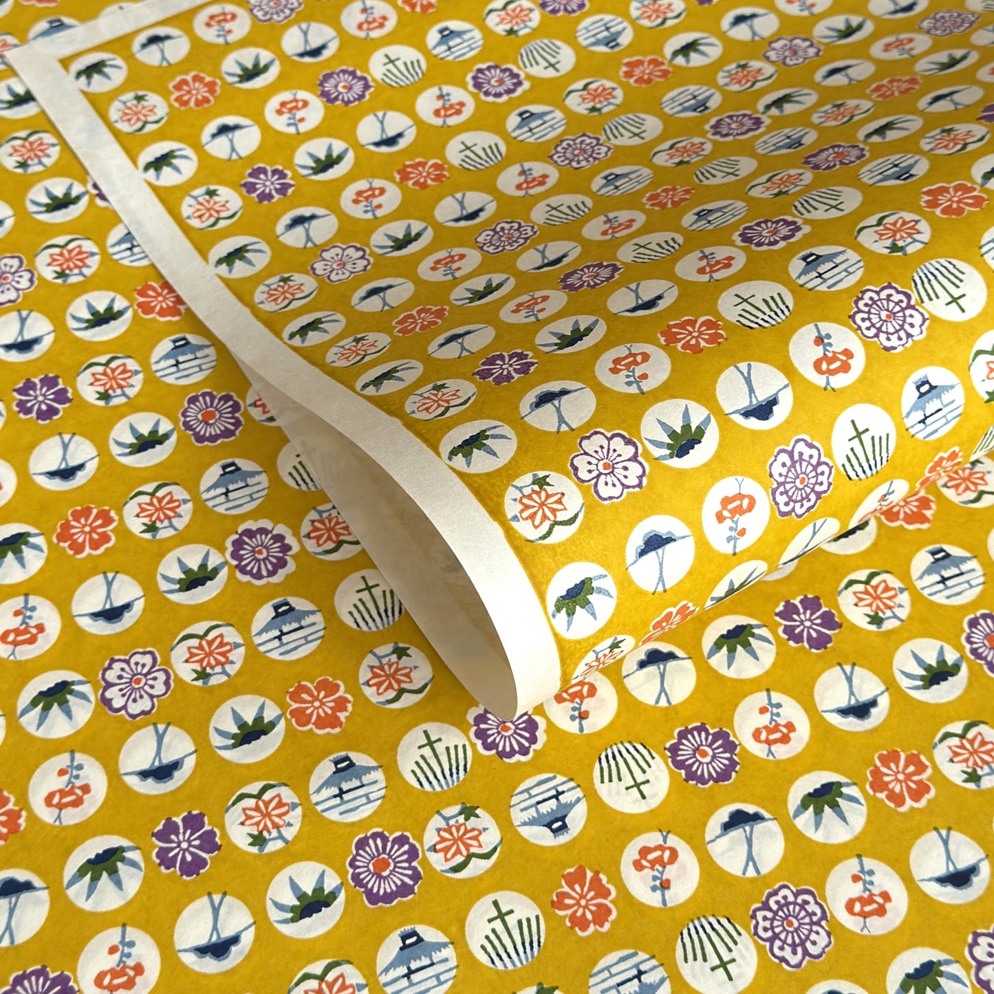 japanese silk-screen handmade paper showing circles of traditional motifs on yellow backdrop