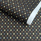 Japanese silkscreen chiyogami paper with a pattern of small repeat motifs in red, blue, lemon and gold on a black background