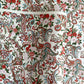 Japanese chiyogami paper silkscreened with a paisley floral style pattern in red, aqua, green and gold on a white background.