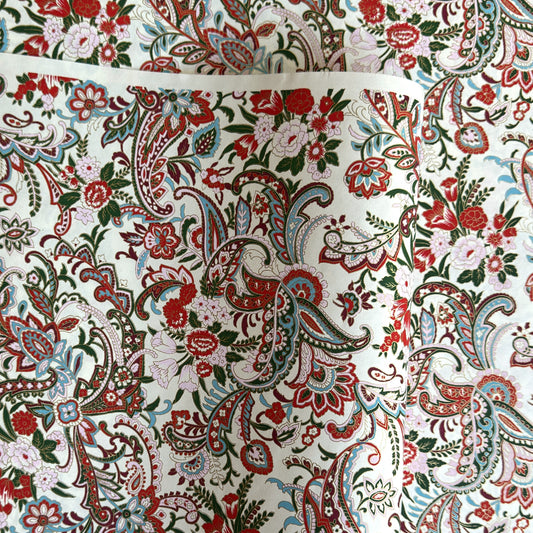 Japanese chiyogami paper silkscreened with a paisley floral style pattern in red, aqua, green and gold on a white background.