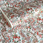 Japanese chiyogami paper silkscreened with a paisley floral style pattern in red, aqua, green and gold on a white background.