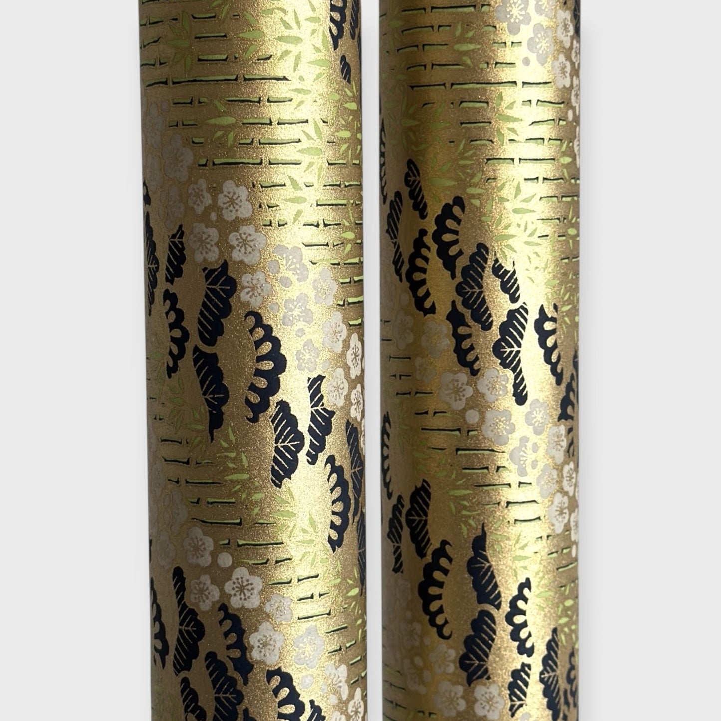 Japanese chiyogami paper with a design of trees, bamboo and plum blossom in indigo, green and white on a vintage gold backdrop.  Rolled