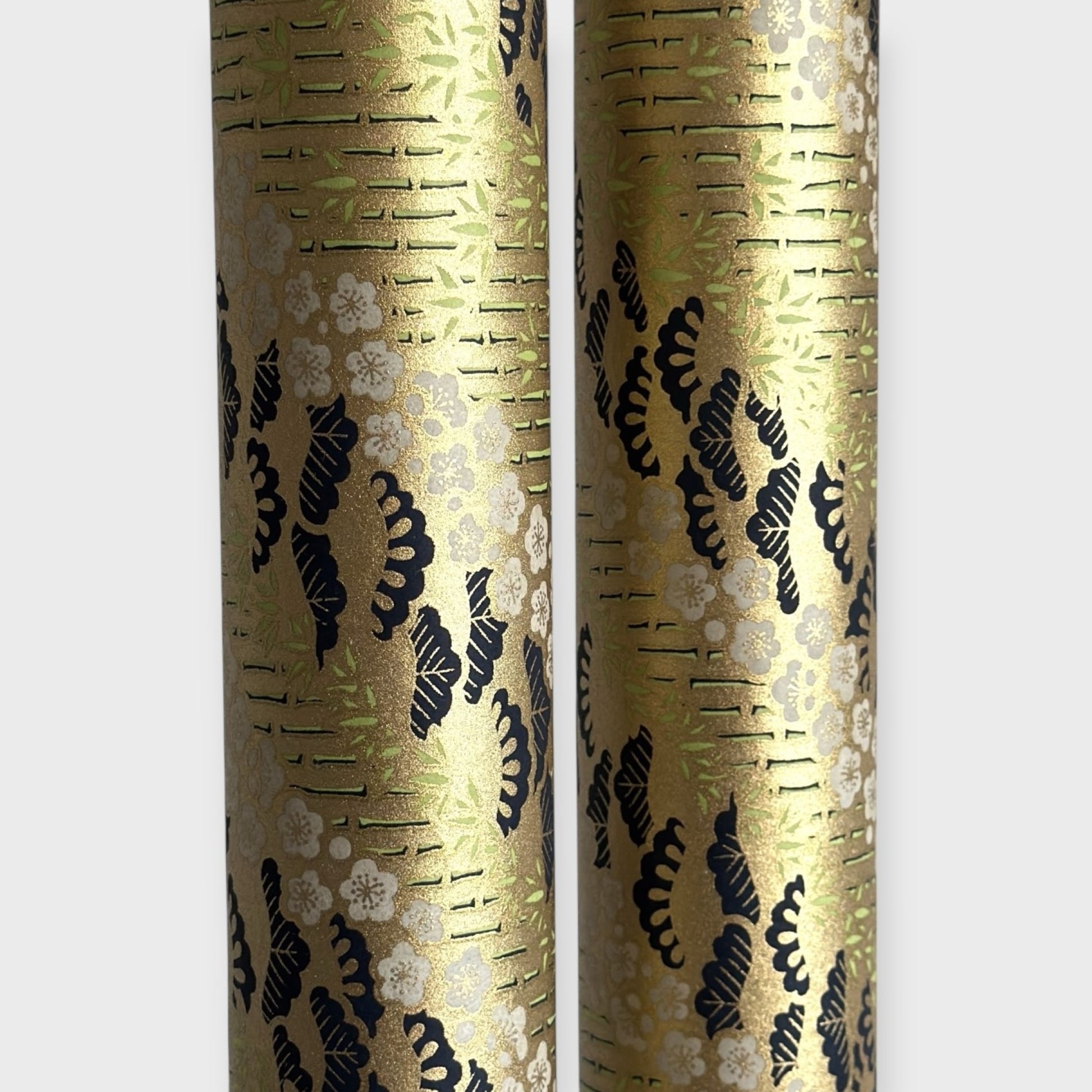 Japanese chiyogami paper with a design of trees, bamboo and plum blossom in indigo, green and white on a vintage gold backdrop.  Rolled