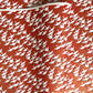 A close-up of a red sheet of Japanese chiyogami paper with an all-over repeating pattern of white cranes and small gold wave-like motifs. 