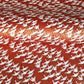 A close-up of a red sheet of Japanese chiyogami paper with an all-over repeating pattern of white cranes and small gold wave-like motifs. 