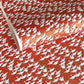 A close-up of a red sheet of Japanese chiyogami paper with an all-over repeating pattern of white cranes and small gold wave-like motifs. 