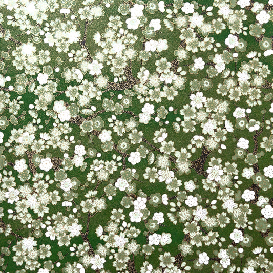 Japanese chiyogami paper with white and pale green blossom flowers on dark green backdrop.