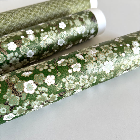Japanese chiyogami paper with white and pale green blossom flowers on dark green backdrop.