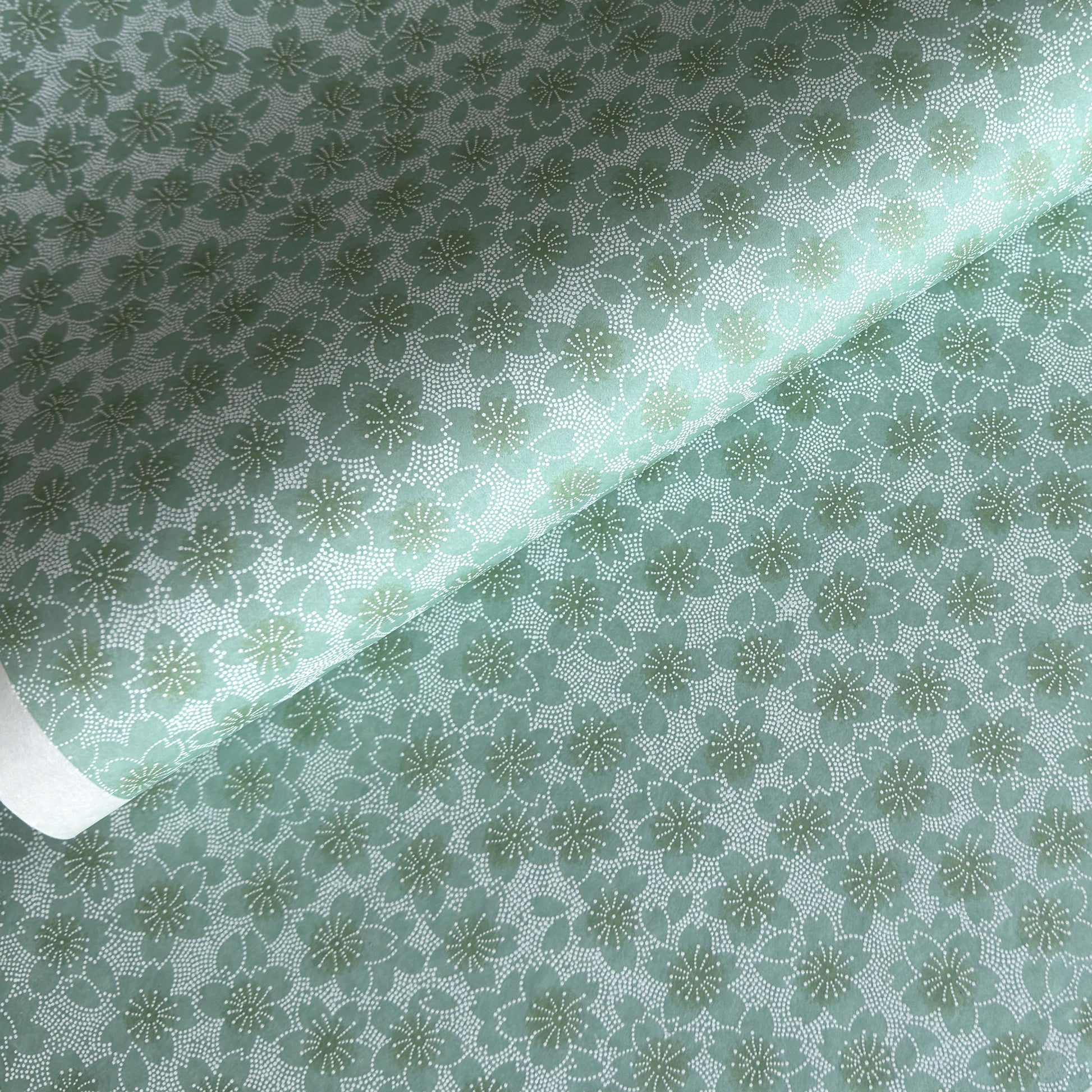 japanese silk-screen paper, chiyogami, with a cherry blossom flower repeat pattern in turquoise and white