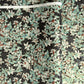 a sheet of Japanese chiyogami screen printed paper with a pattern of light green foliage on a black ground with silver botanical details