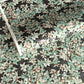 a sheet of Japanese chiyogami screen printed paper with a pattern of light green foliage on a black ground with silver botanical details