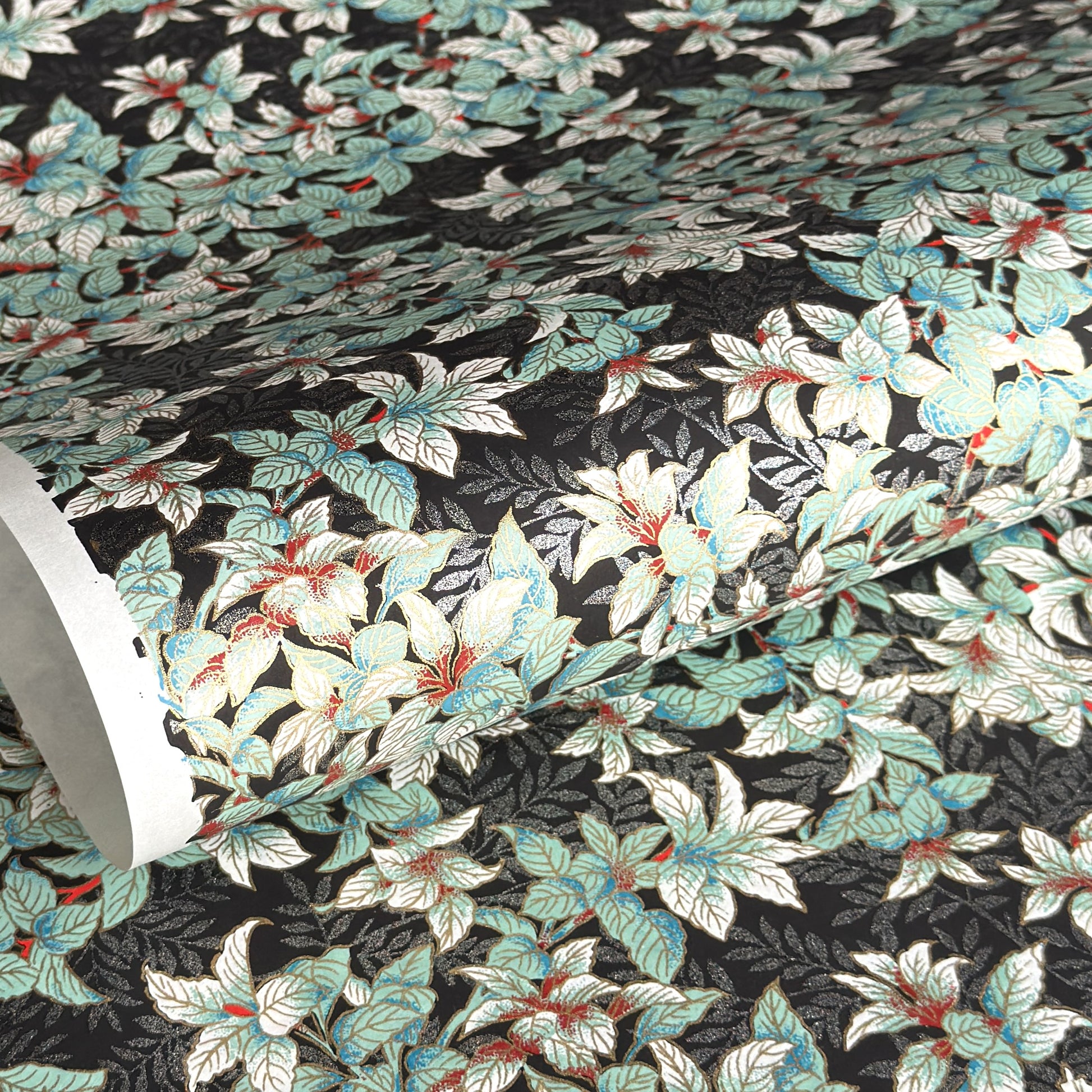 a sheet of Japanese chiyogami screen printed paper with a pattern of light green foliage on a black ground with silver botanical details