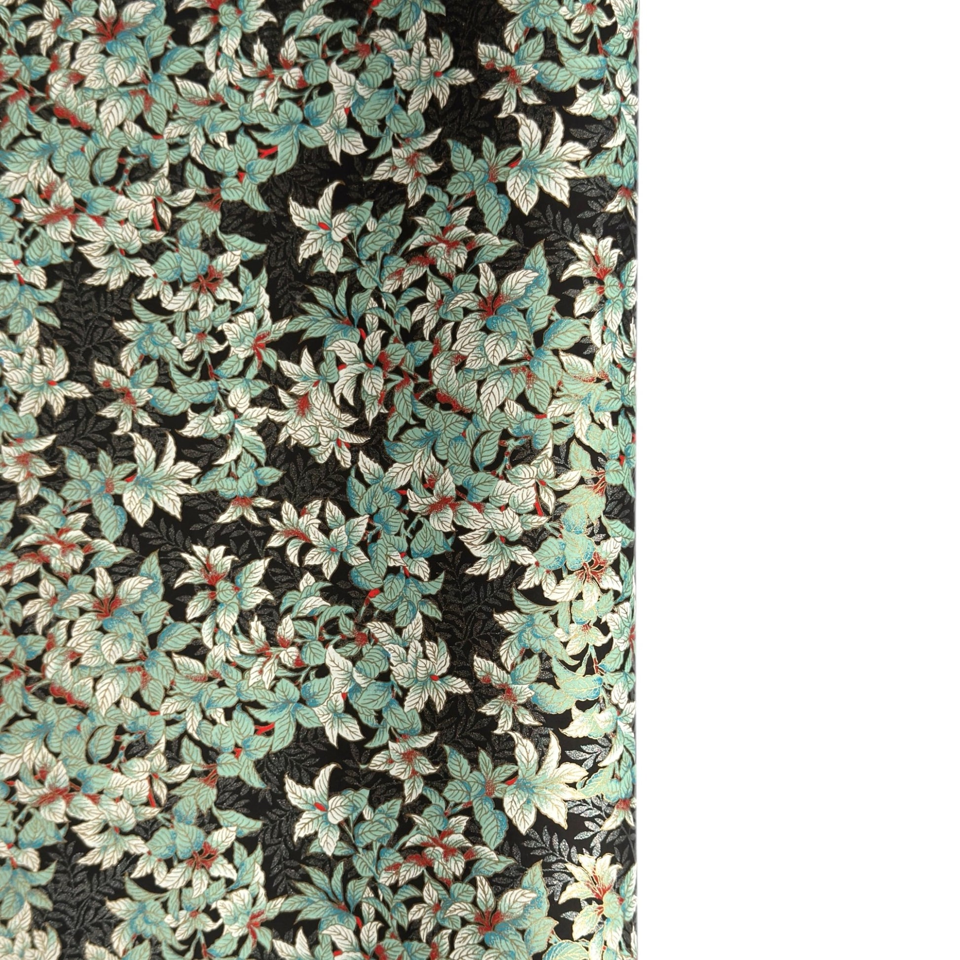 a sheet of Japanese chiyogami screen printed paper with a pattern of light green foliage on a black ground with silver botanical details