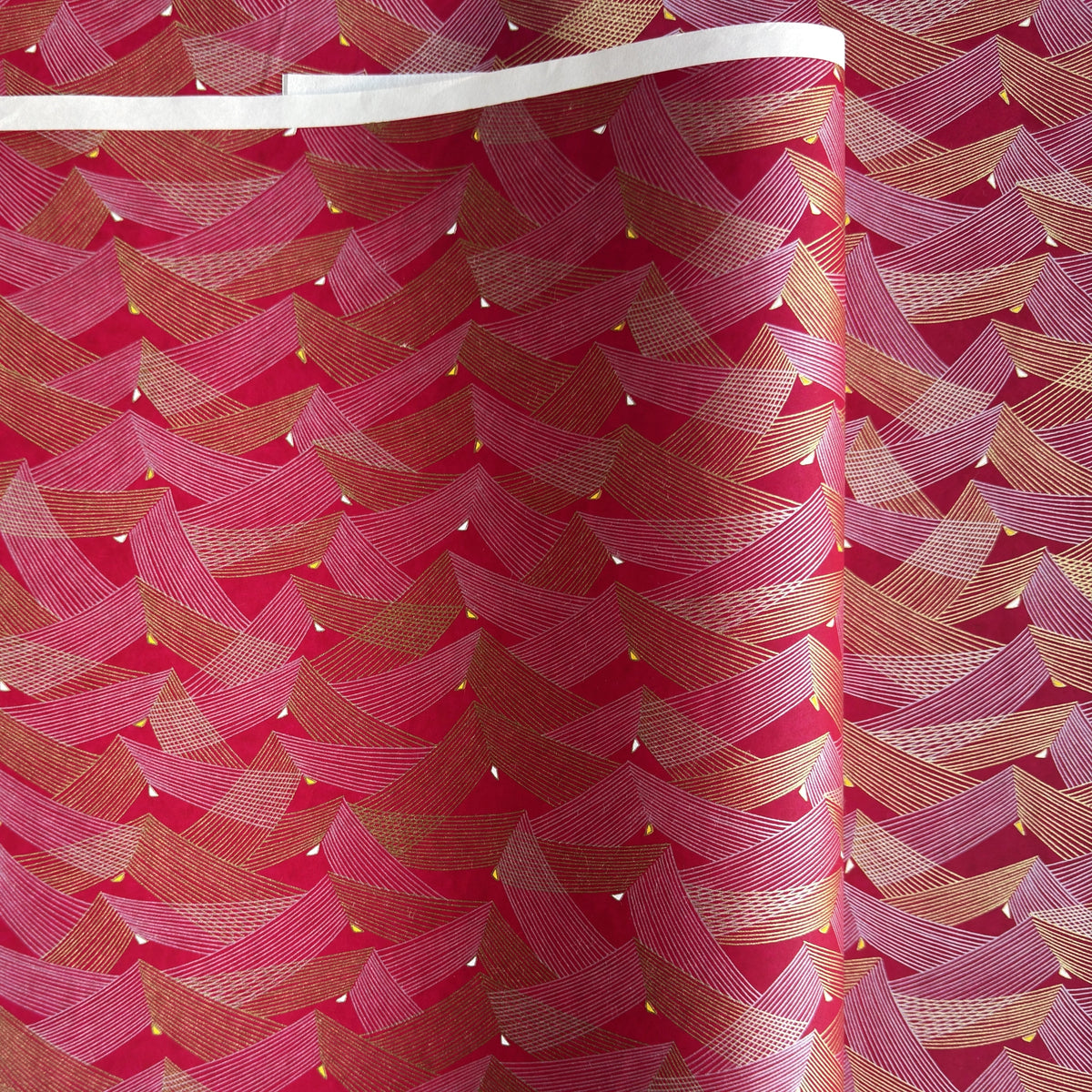 a sheet of Japanese chiyogami paper with a pattern of gold and pink striped chevron lines on fuchsia ground