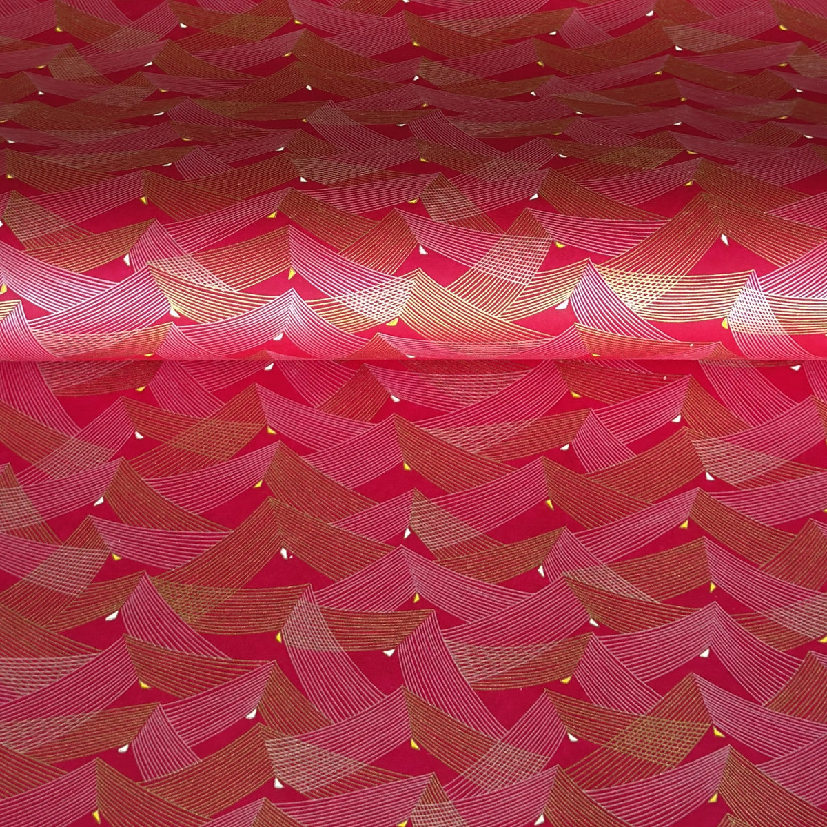 a sheet of Japanese chiyogami paper with a pattern of gold and pink striped chevron lines on fuchsia ground