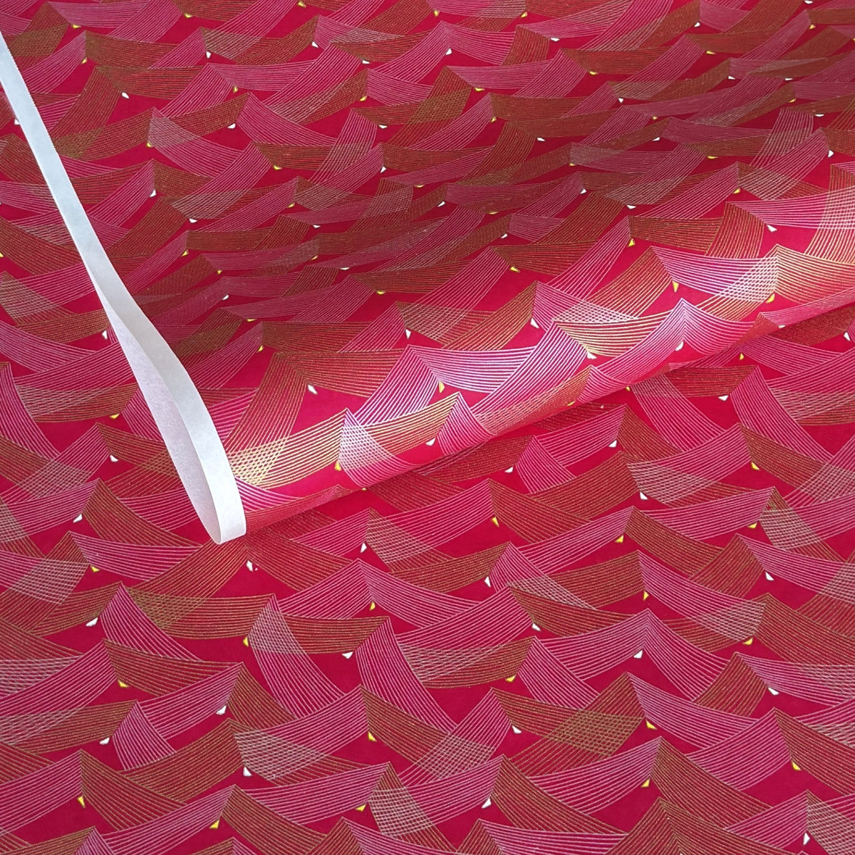 a sheet of Japanese chiyogami paper with a pattern of gold and pink striped chevron lines on fuchsia ground