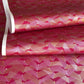 a sheet of Japanese chiyogami paper with a pattern of gold and pink striped chevron lines on fuchsia ground