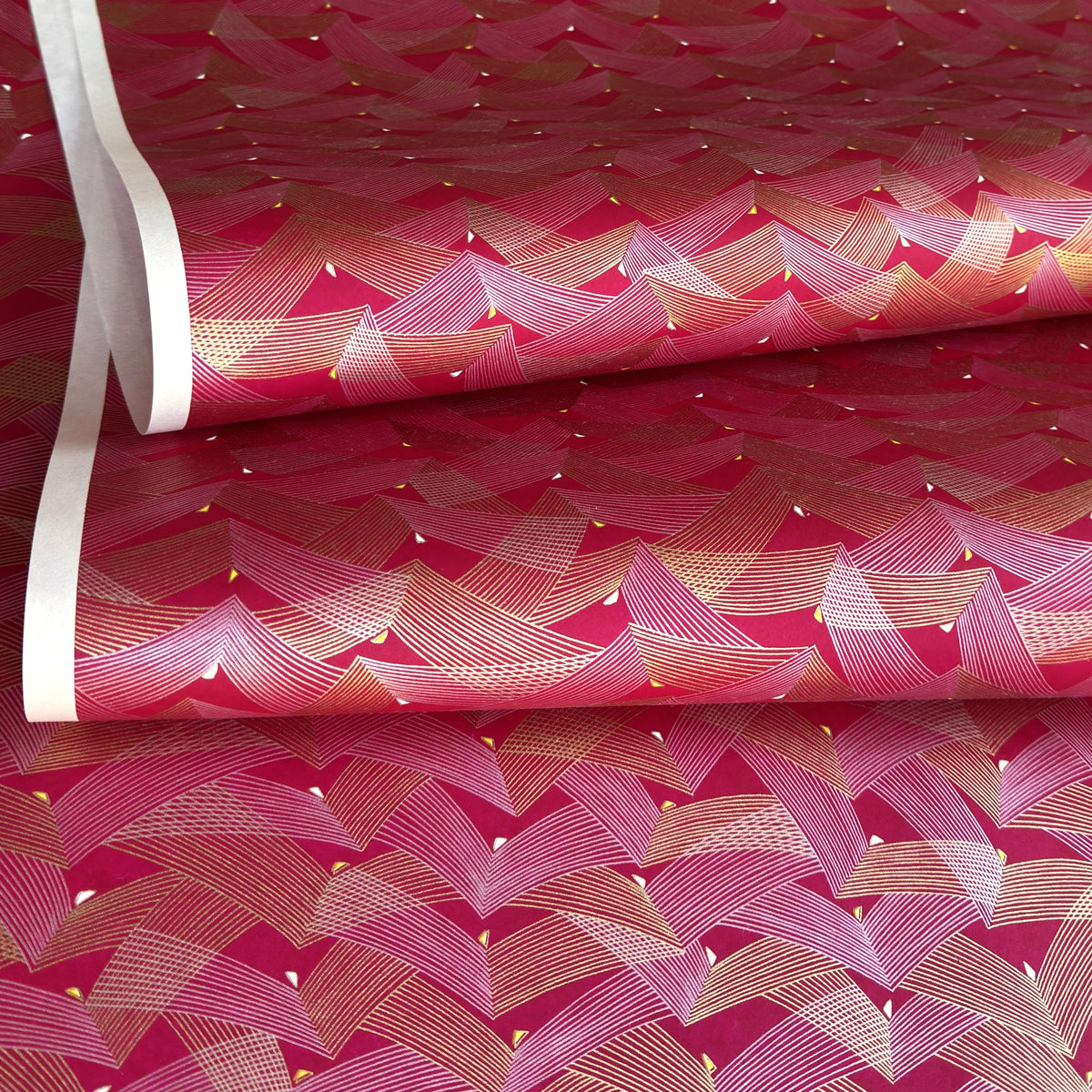 a sheet of Japanese chiyogami paper with a pattern of gold and pink striped chevron lines on fuchsia ground