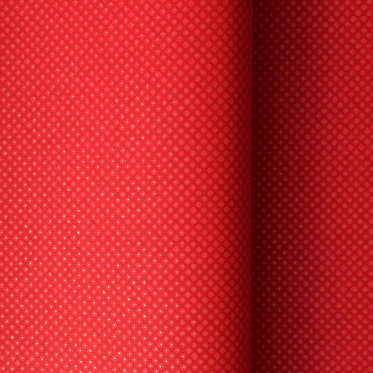 A close-up of a bright red sheet of chiyogami paper with a fine dotted pattern in gold. 